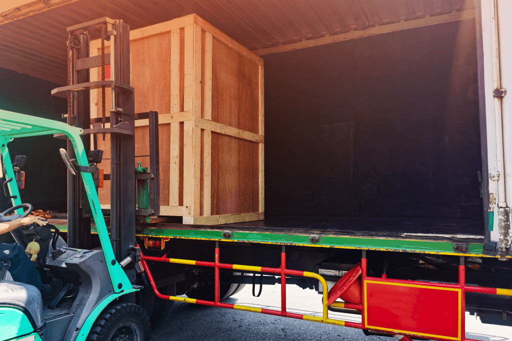 forklift loading a wooden crate onto a truck