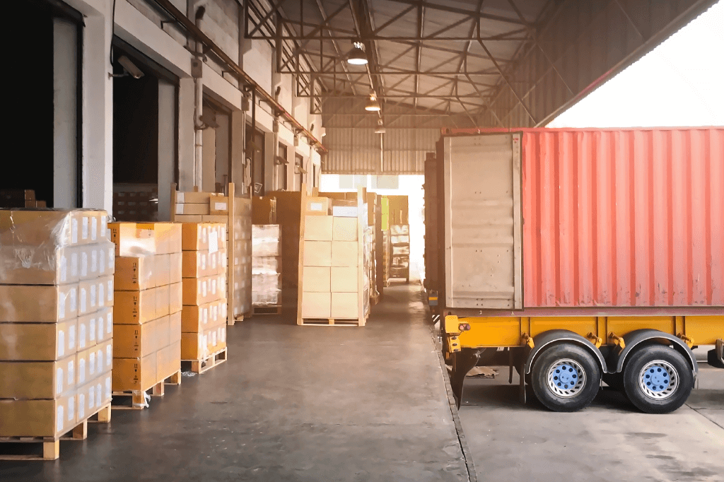 Trailer backed to a dock with pallets waiting to be loaded.