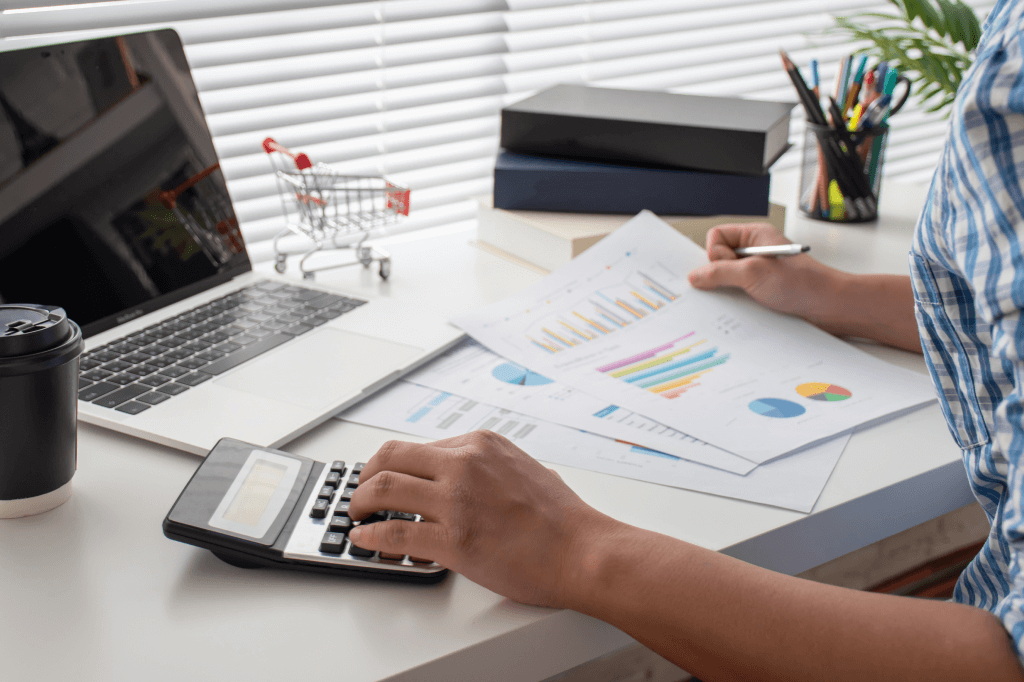 Seated person reviewing spreadsheets and using a calculator.