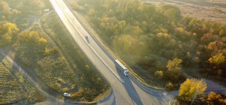 Truck on a highway approaching an intersection.