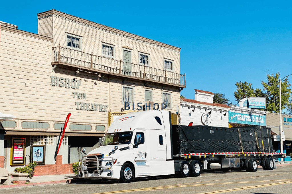 Flatbed truck parked in front of a business on a city street.