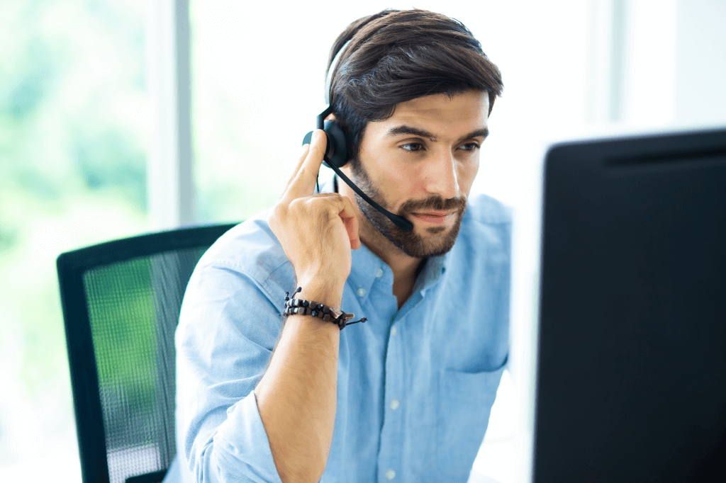 person wearing a headset seated at a desk using a computer.