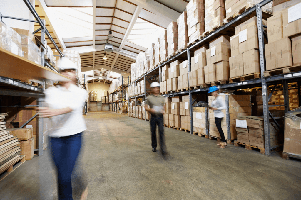 people in a warehouse with racks of packages