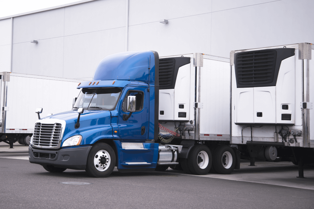 Regional truck backing a refrigerated trailer up to a dock.