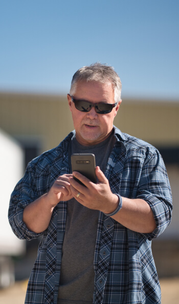 A truck driver uses his phone to find expedited loads on Truckstop.com.
