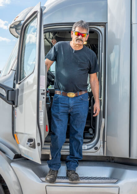 Truckstop.com customer stepping out of the cab of his gray heavy hauler.