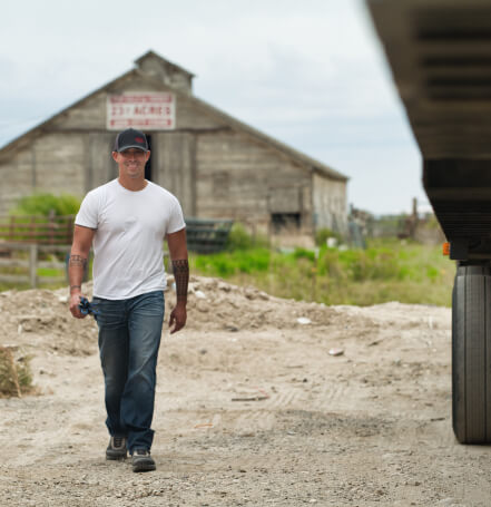 Truckstop customer walks to his truck with a large barn in the background.